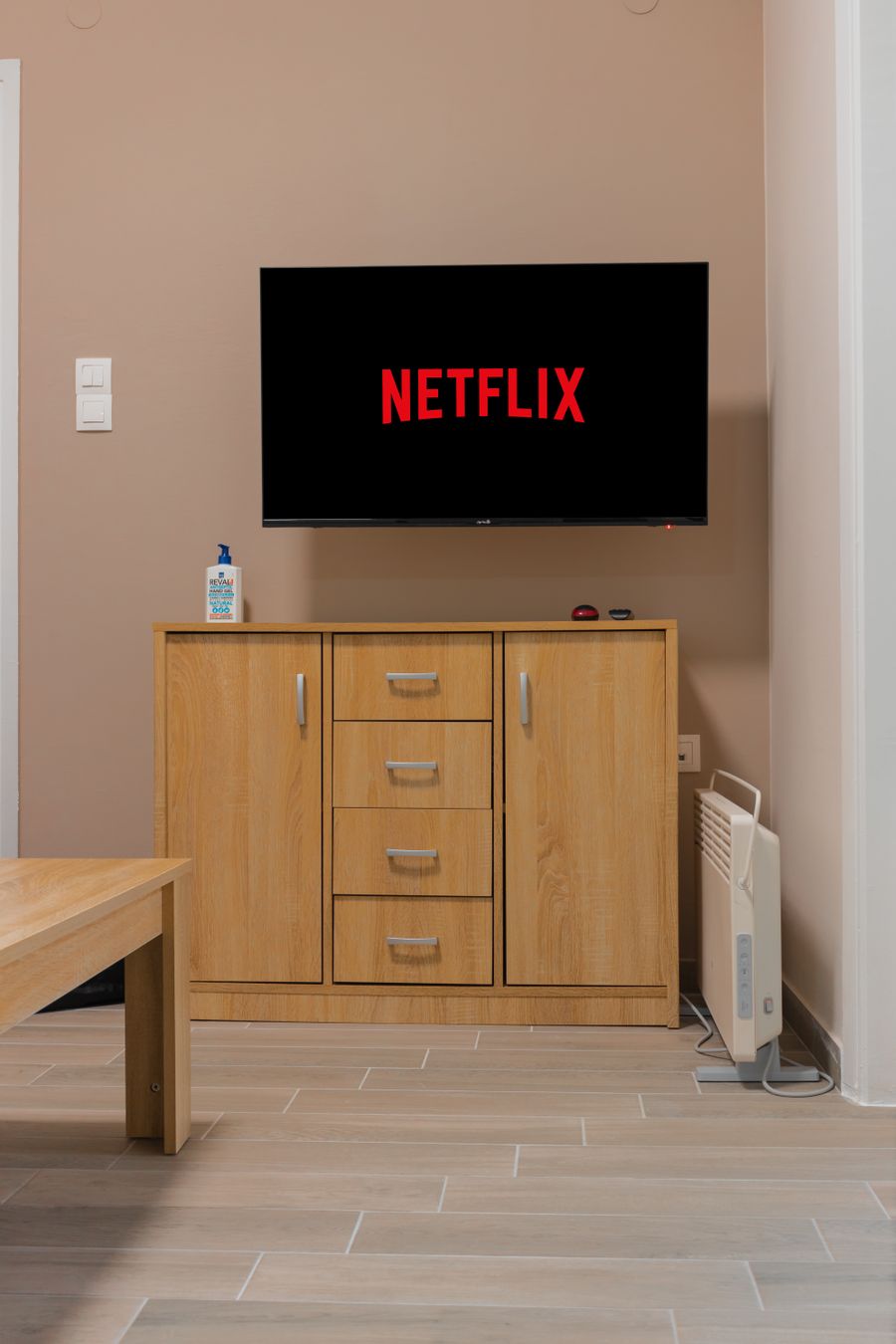 Wooden TV cabinet with drawers under a wall mounted TV